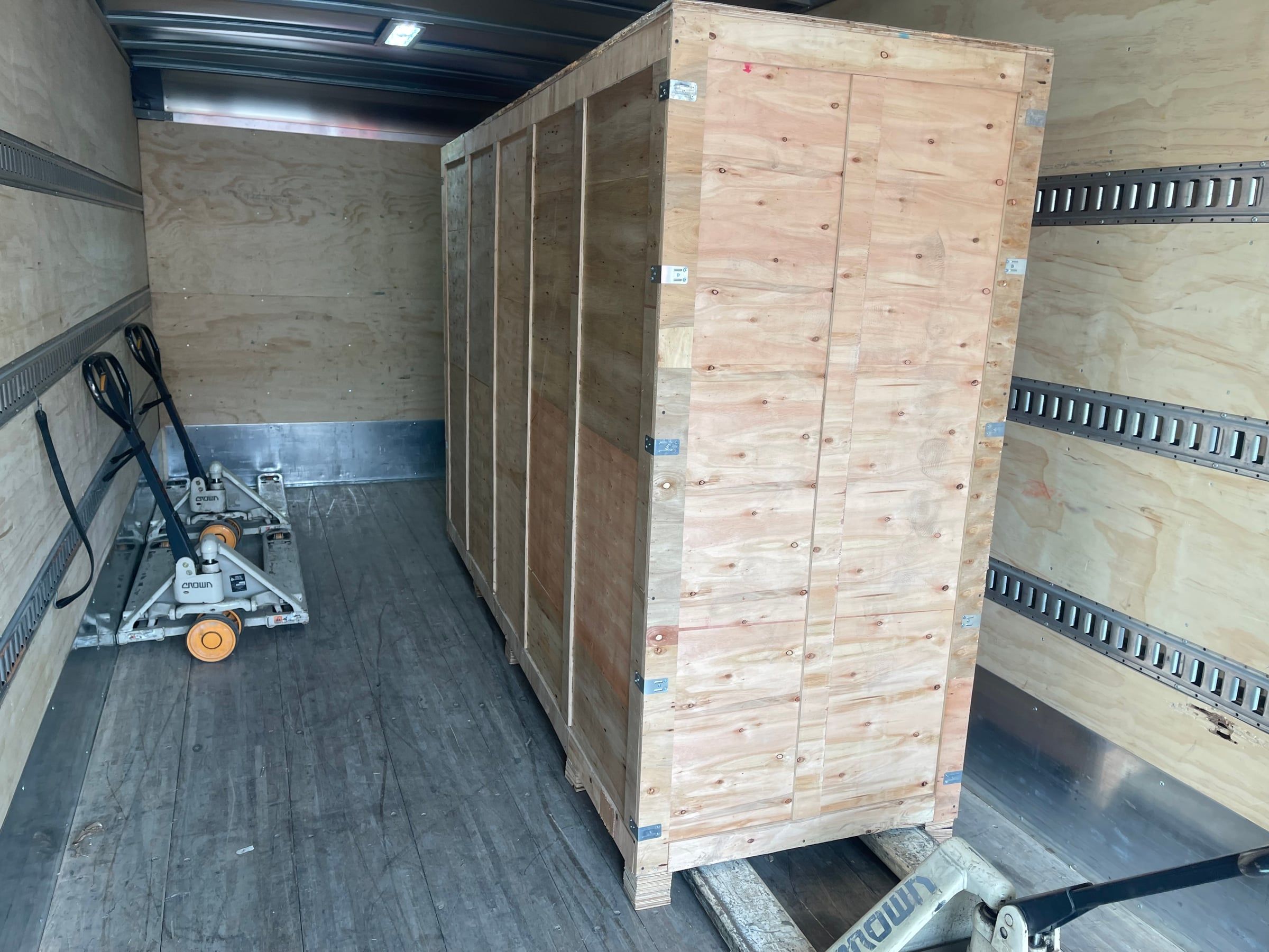 A tall wooden crate loaded and strapped inside our truck
