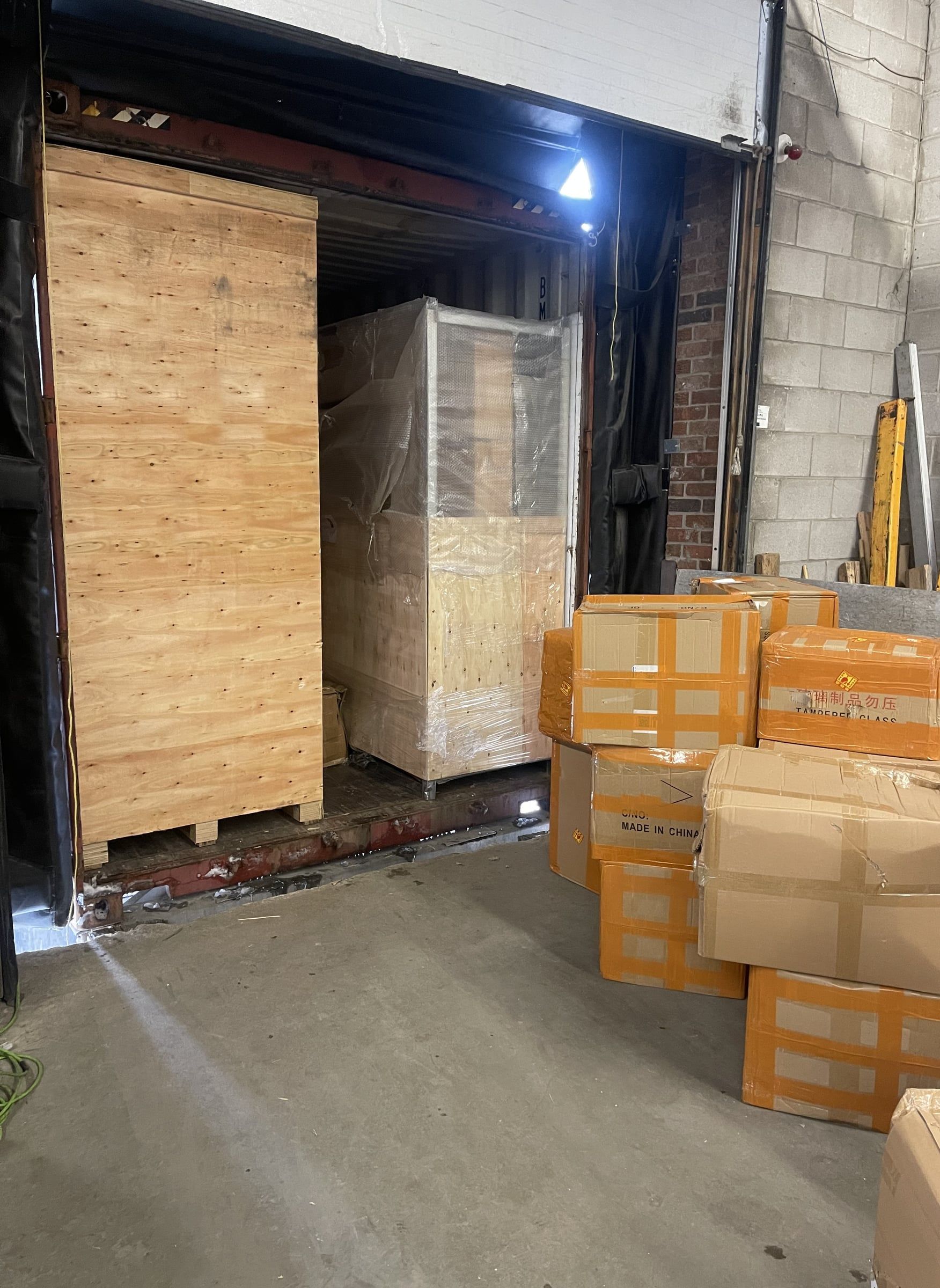 A tall crate at the door of a container at our dock, with cartons already unloaded
