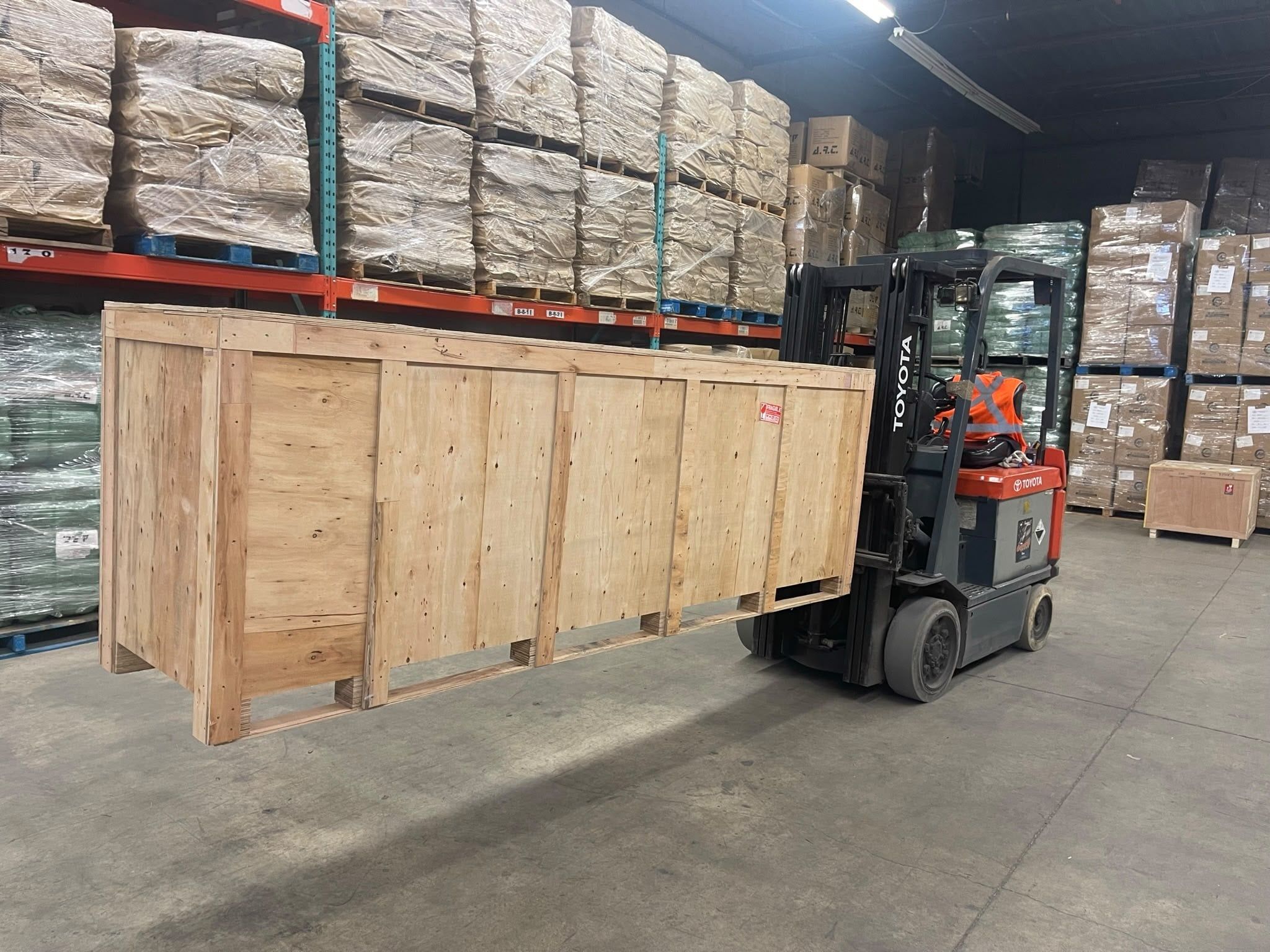 Forklift moving a crated shipment into storage in our warehouse