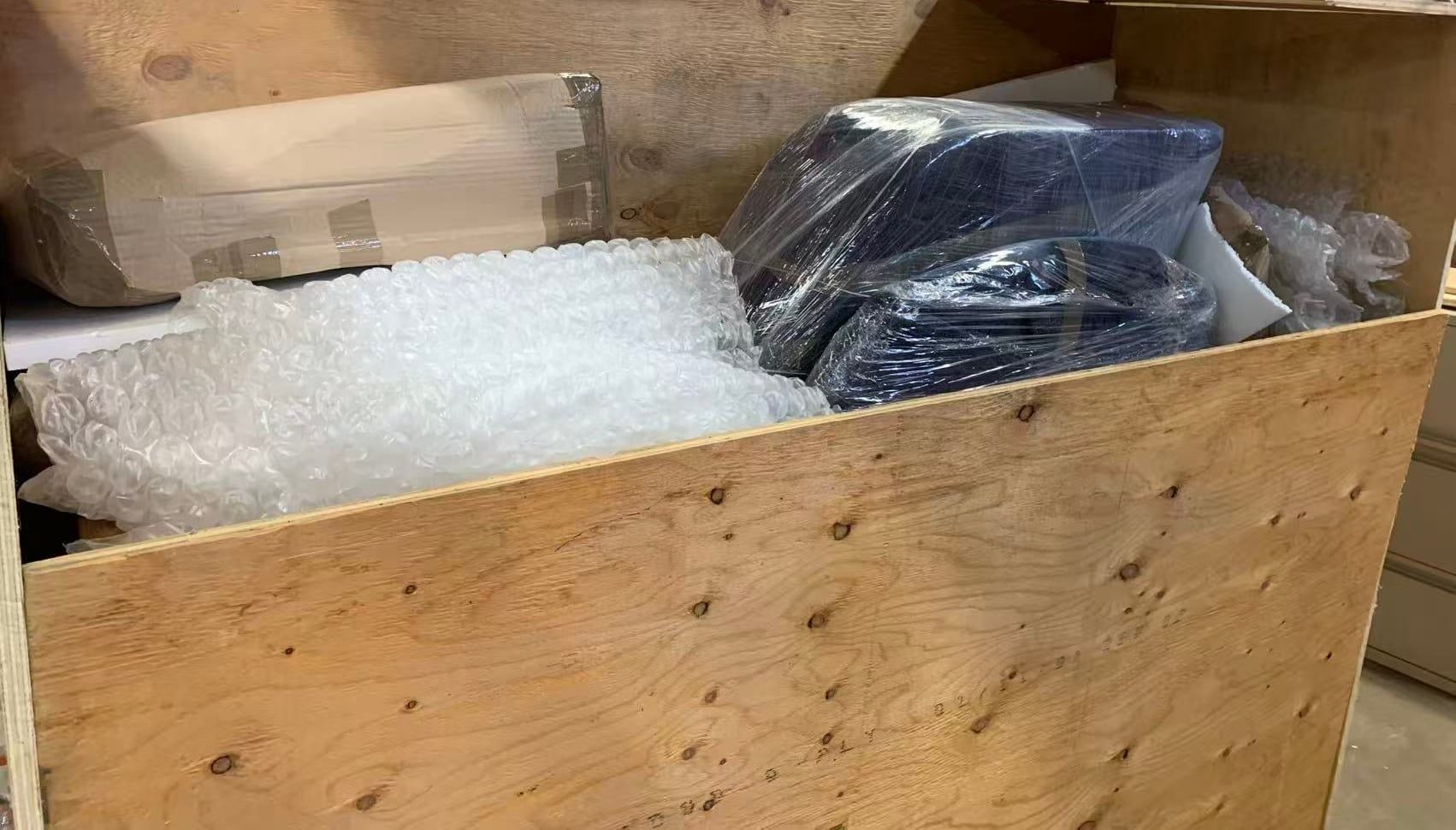 Wrapped items packed into a wooden crate with bubble wrap
