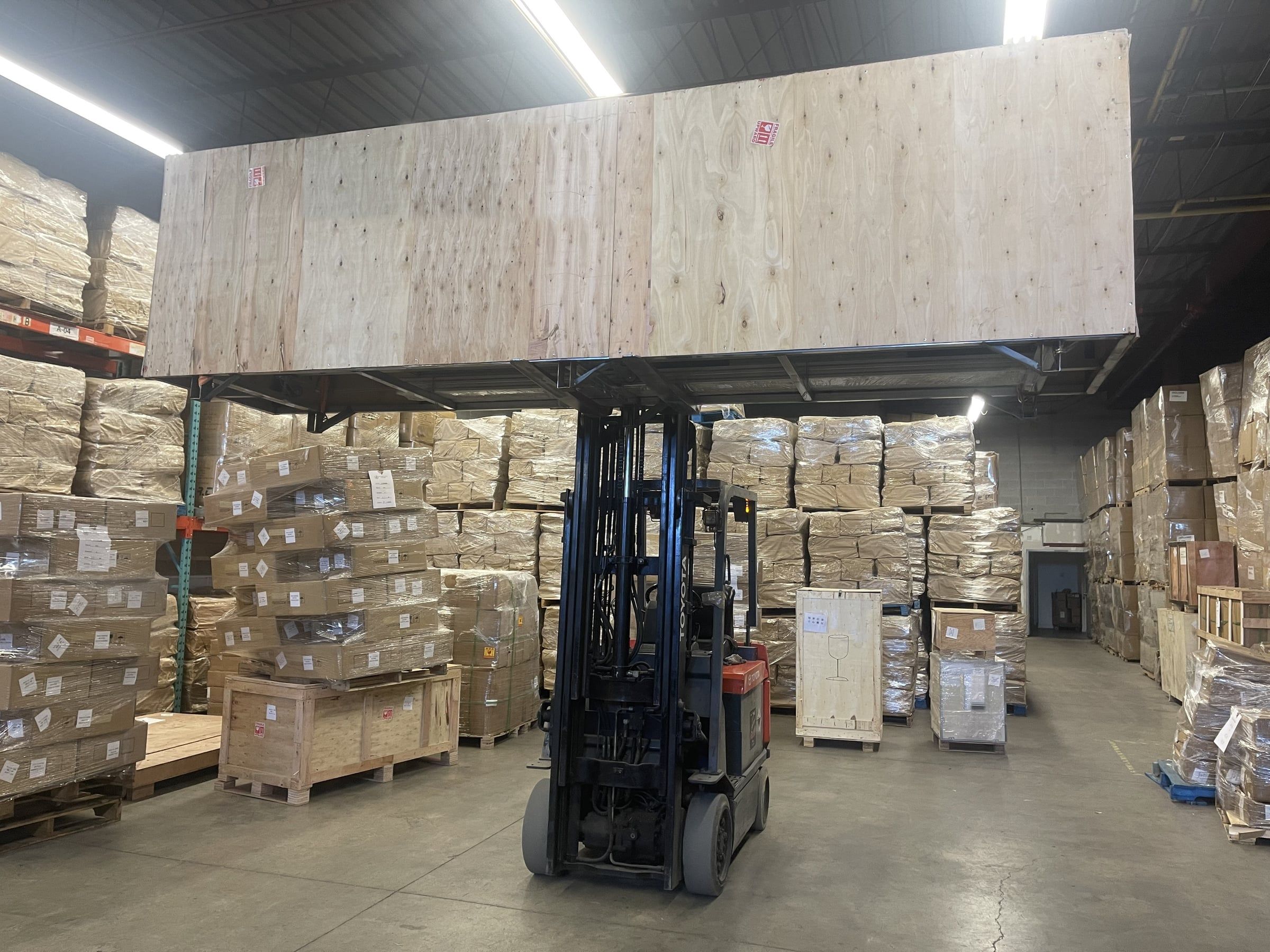 Our forklift lifting a long wooden crate high in the warehouse