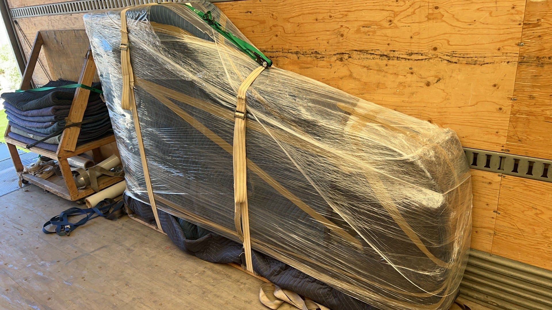 A grand piano padded, wrapped and strapped on a piano board in our truck